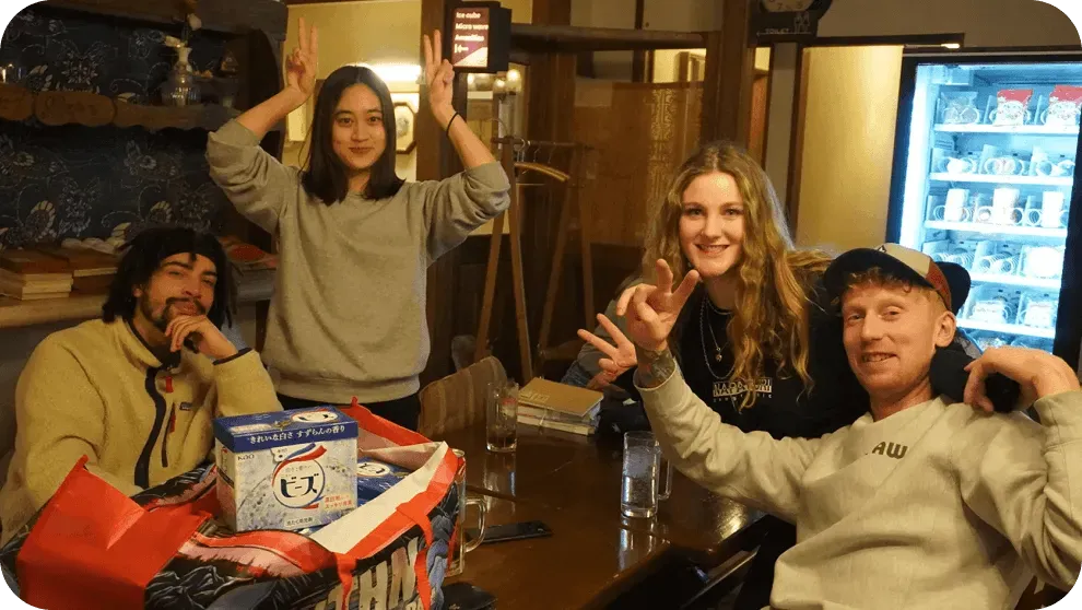 宿のラウンジで外国人の友人たちとテーブルを囲む参加者